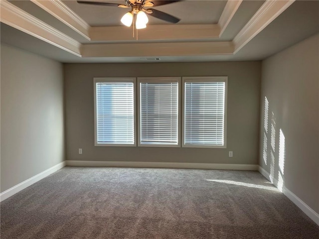 empty room with a raised ceiling, ceiling fan, carpet floors, and ornamental molding