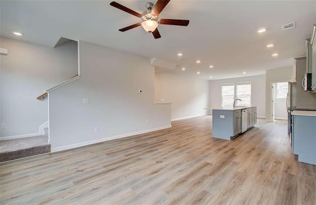 unfurnished living room featuring sink, ceiling fan, and light wood-type flooring