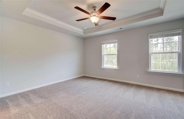 empty room with ceiling fan, carpet flooring, and a tray ceiling