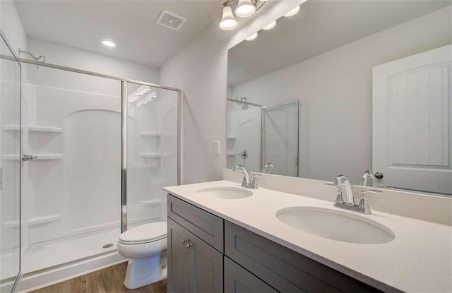 bathroom with hardwood / wood-style flooring, vanity, toilet, and a shower with shower door