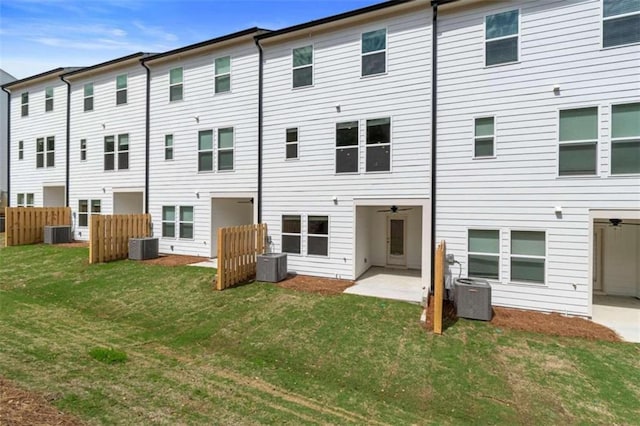 rear view of house featuring a patio, central air condition unit, and a lawn