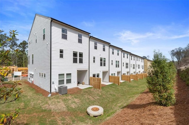 rear view of property with a fire pit, a lawn, and central air condition unit