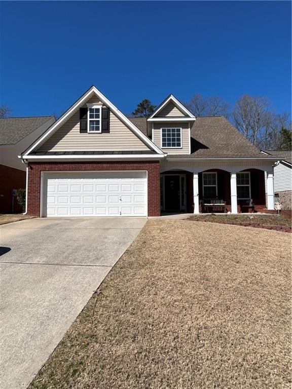 view of front of property featuring a porch, an attached garage, brick siding, concrete driveway, and roof with shingles