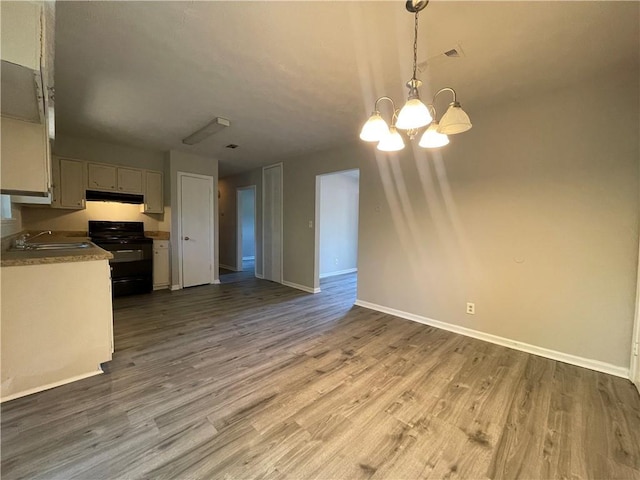 33 Drew Ct, Jonesboro, GA 30238 - kitchen with black range oven, under cabinet range hood, a chandelier, wood finished floors, and pendant lighting