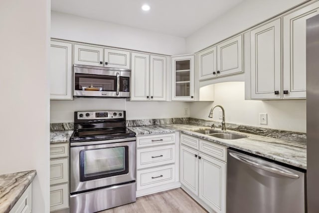 kitchen featuring white cabinetry, sink, stainless steel appliances, and light stone countertops