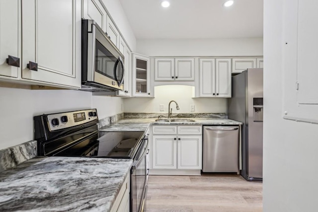 kitchen featuring white cabinetry, sink, light stone counters, and appliances with stainless steel finishes