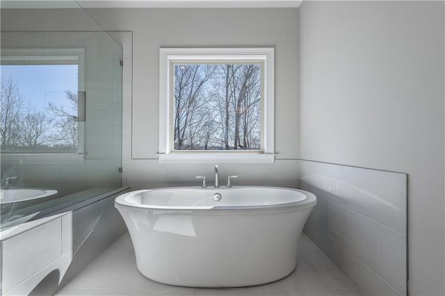 full bathroom featuring tile patterned floors, vanity, a freestanding tub, and tile walls