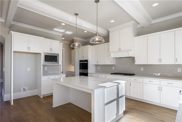 kitchen with a center island, under cabinet range hood, stainless steel appliances, beamed ceiling, and white cabinets