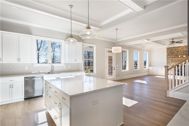 kitchen with stainless steel dishwasher, backsplash, beam ceiling, and a sink
