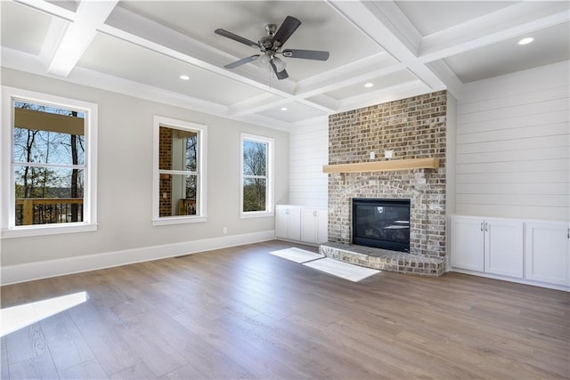 unfurnished living room featuring coffered ceiling, baseboards, beamed ceiling, a fireplace, and wood finished floors