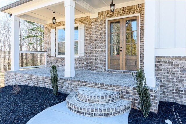 entrance to property with french doors, brick siding, and a porch
