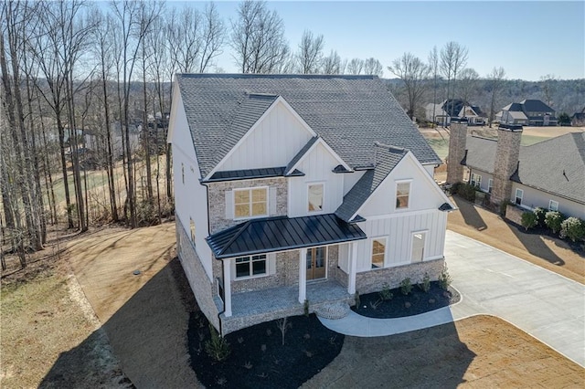modern inspired farmhouse with stone siding, board and batten siding, a standing seam roof, and metal roof