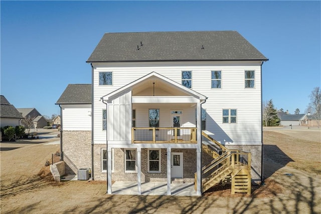 back of house with stairs, central air condition unit, brick siding, a shingled roof, and a patio