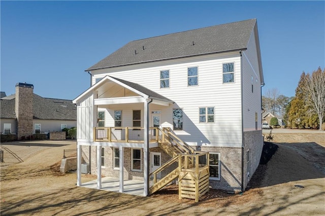 back of house with brick siding, stairway, and a patio