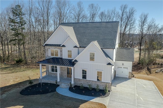 modern farmhouse with driveway, stone siding, a standing seam roof, board and batten siding, and metal roof
