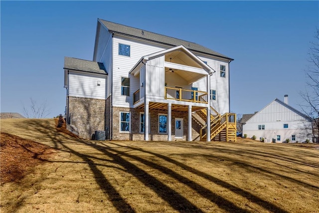 rear view of house featuring ceiling fan, stairway, brick siding, cooling unit, and a yard