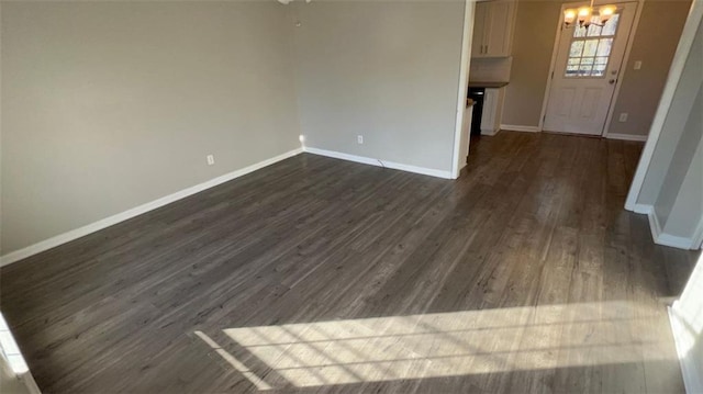 unfurnished living room with dark hardwood / wood-style flooring and a chandelier