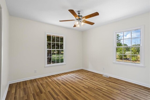 unfurnished room with ceiling fan, a wealth of natural light, and wood-type flooring