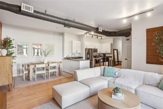 living area featuring light wood finished floors, visible vents, and track lighting