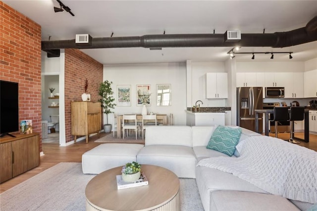 living room with track lighting, visible vents, and light wood-type flooring