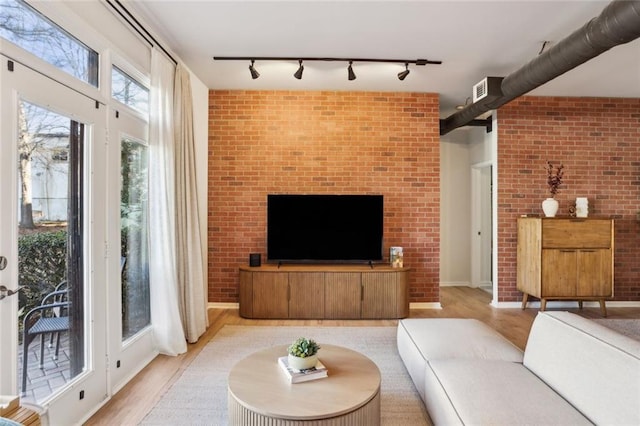 living area featuring brick wall and light wood finished floors