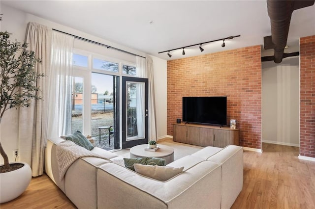 living area featuring baseboards, light wood-style flooring, and rail lighting