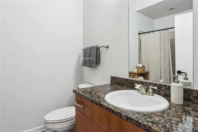 bathroom with vanity, a shower with shower curtain, toilet, and baseboards