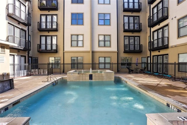 view of swimming pool featuring a patio area, a pool with connected hot tub, and fence