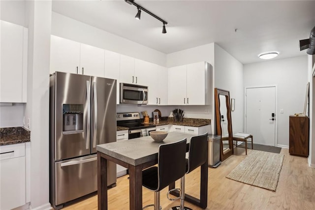 kitchen featuring track lighting, light wood-style flooring, appliances with stainless steel finishes, and white cabinetry