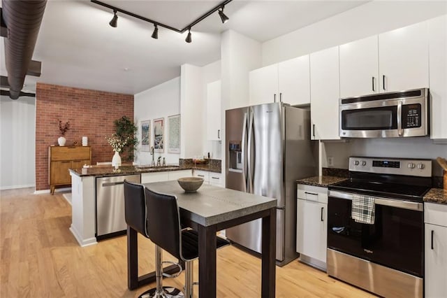 kitchen with light wood finished floors, white cabinetry, a peninsula, and stainless steel appliances