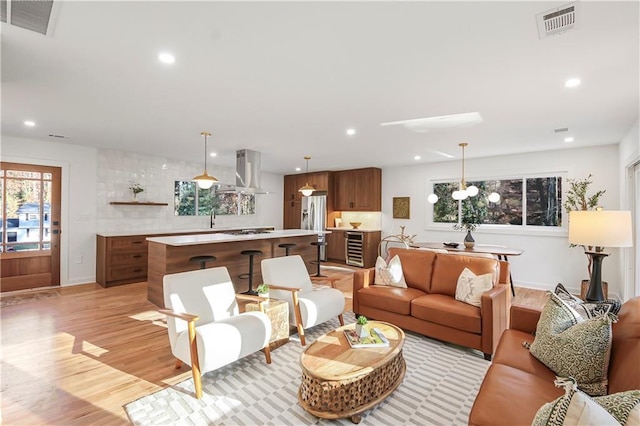 living room featuring visible vents, recessed lighting, light wood finished floors, and wine cooler