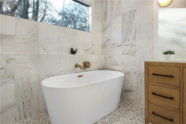 full bathroom featuring a freestanding tub and tile walls