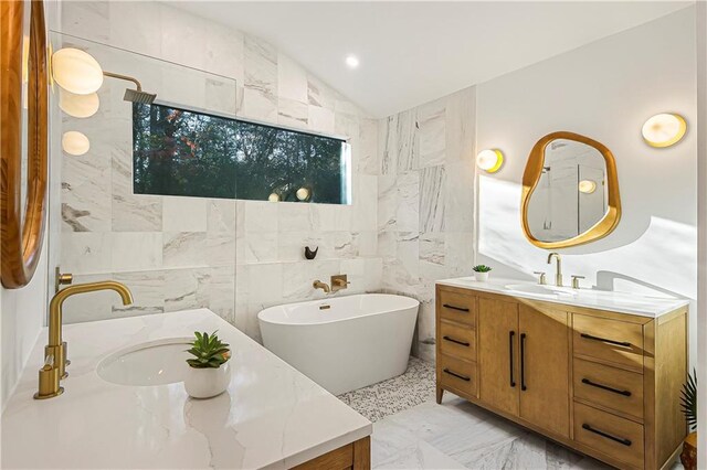full bath featuring vanity, marble finish floor, a freestanding tub, tile walls, and lofted ceiling