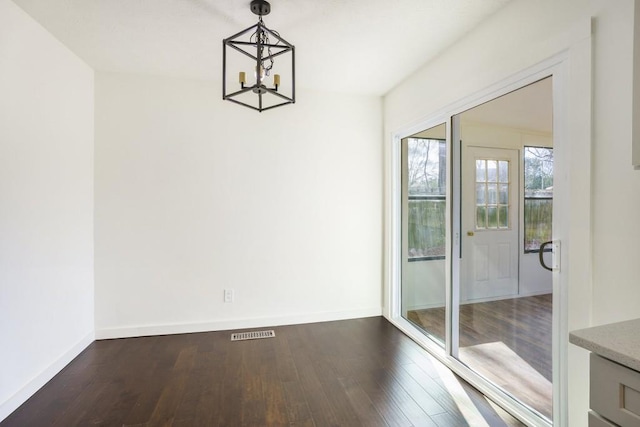 unfurnished dining area featuring a chandelier, baseboards, visible vents, and dark wood-style floors