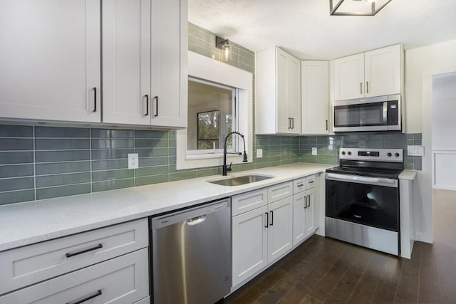 kitchen featuring tasteful backsplash, light stone counters, a sink, stainless steel appliances, and white cabinets