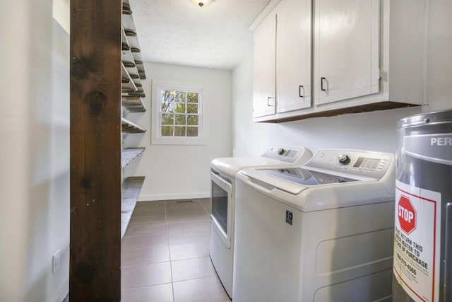 laundry area with cabinet space, tile patterned floors, baseboards, electric water heater, and independent washer and dryer