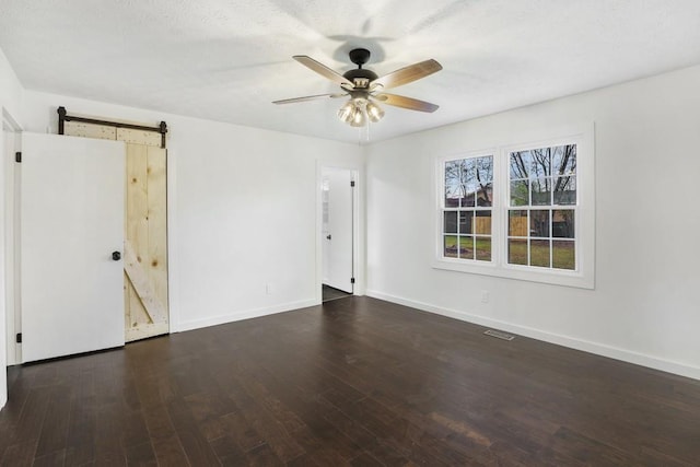 unfurnished room with a barn door, baseboards, and wood finished floors