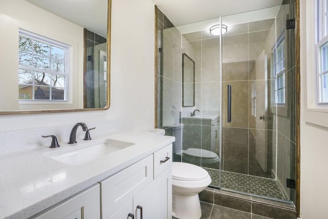 full bathroom featuring toilet, tile patterned floors, vanity, and a stall shower