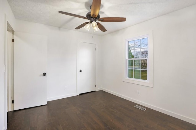 spare room with baseboards, visible vents, and dark wood-style floors