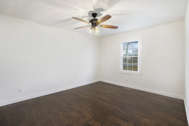 spare room with baseboards, visible vents, ceiling fan, and dark wood-style floors