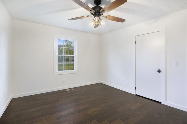 unfurnished room featuring visible vents, baseboards, a ceiling fan, and dark wood-style floors