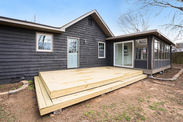 back of property with a wooden deck and a sunroom