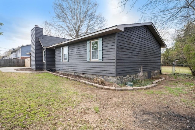 view of home's exterior with a yard, fence, and a chimney