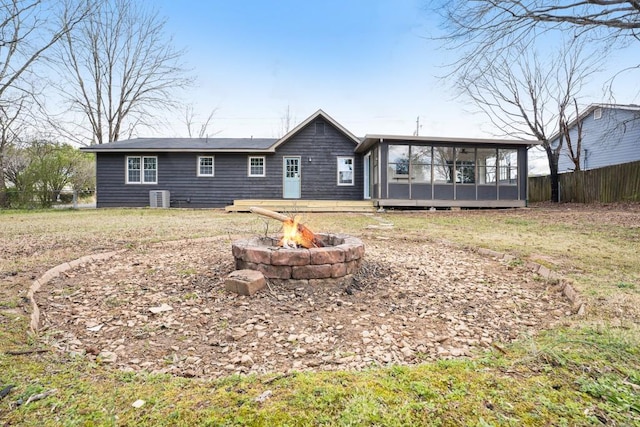 back of house with fence, central AC, a yard, an outdoor fire pit, and a sunroom