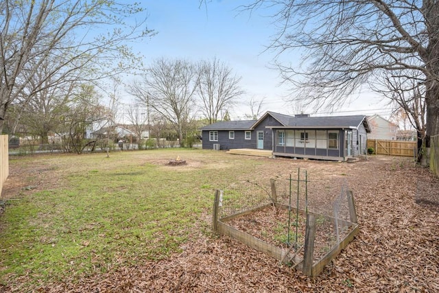view of yard featuring a deck, a fire pit, a garden, and a fenced backyard