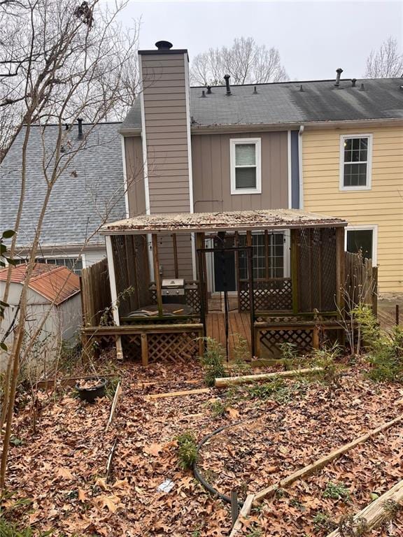 rear view of house featuring board and batten siding, a chimney, and fence