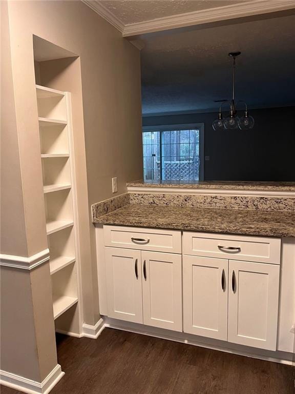 kitchen featuring dark stone countertops, pendant lighting, crown molding, and white cabinets