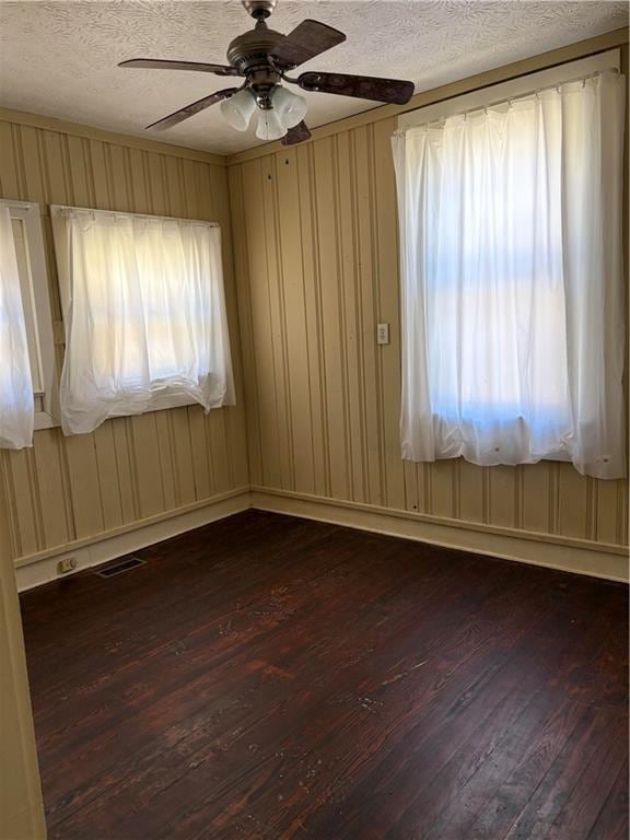 unfurnished room featuring dark wood finished floors, visible vents, a textured ceiling, and ceiling fan