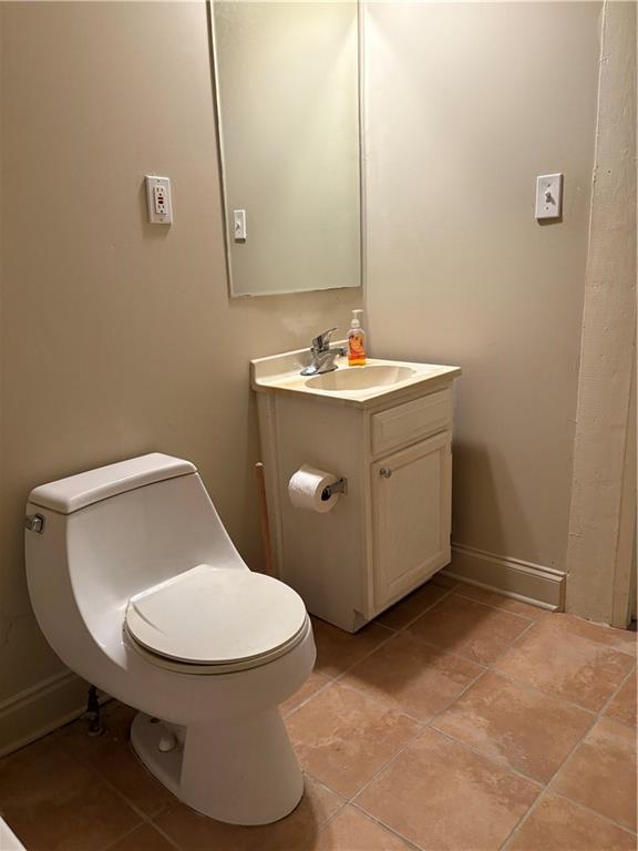 bathroom with vanity, toilet, baseboards, and tile patterned flooring