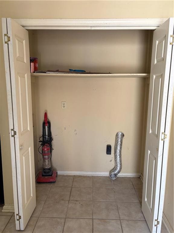 laundry room featuring electric dryer hookup, baseboards, and light tile patterned floors